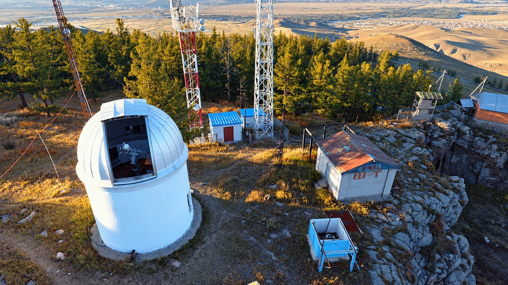 Aerial view of the observatory dome, telescope opening, and surrounding hillside