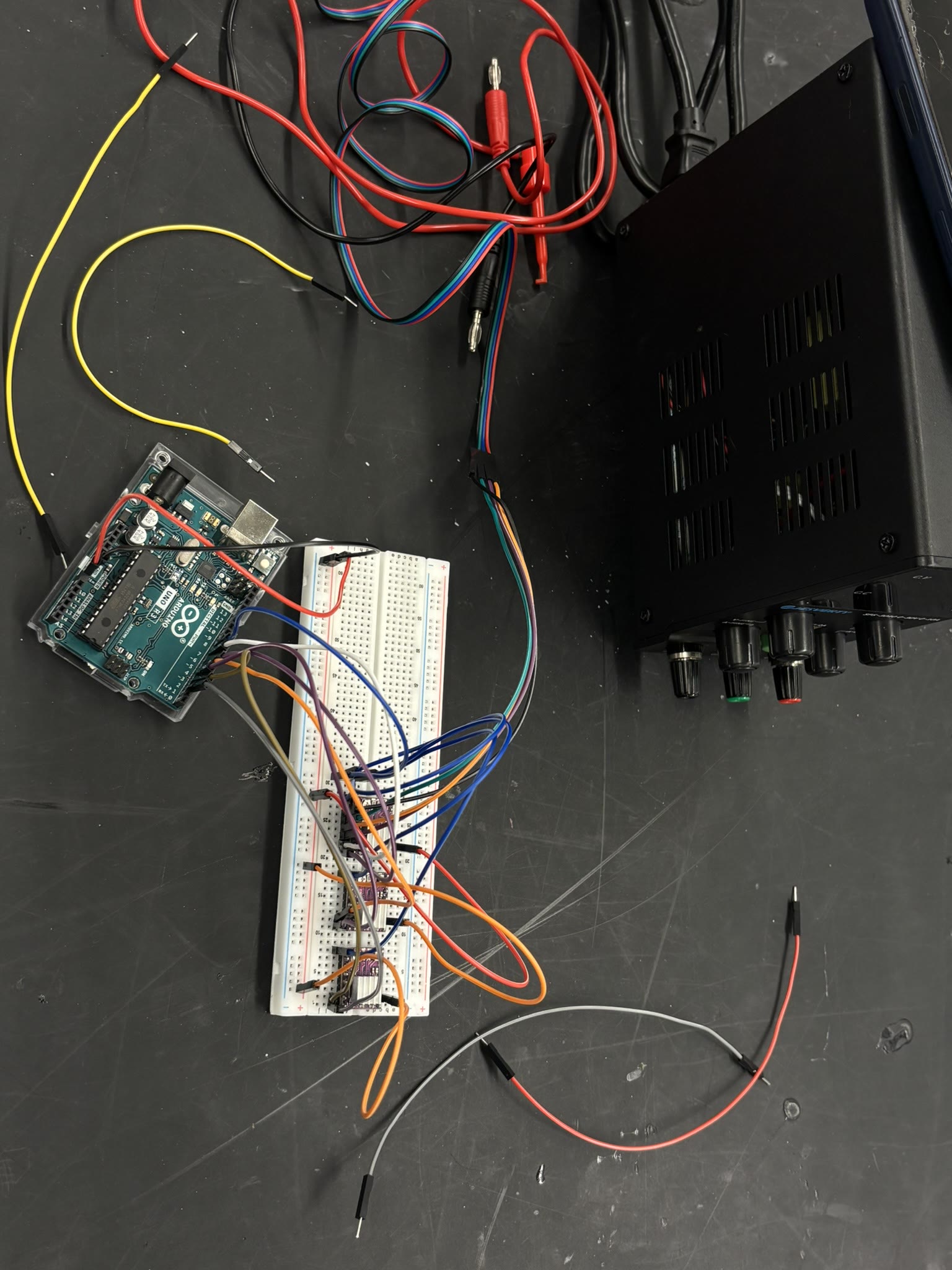 Arduino, breadboard wiring, and bench power equipment used during integration