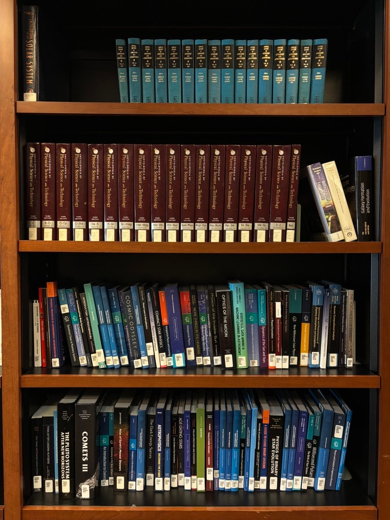 Astronomy reference volumes on wooden shelves