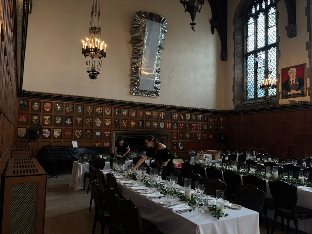 Tables being set in a wood-paneled dining hall
