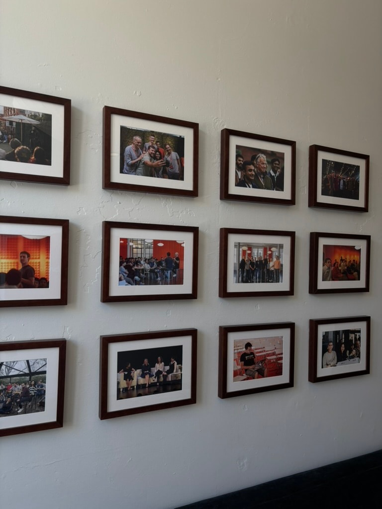 A wall of framed photographs of talks and gatherings