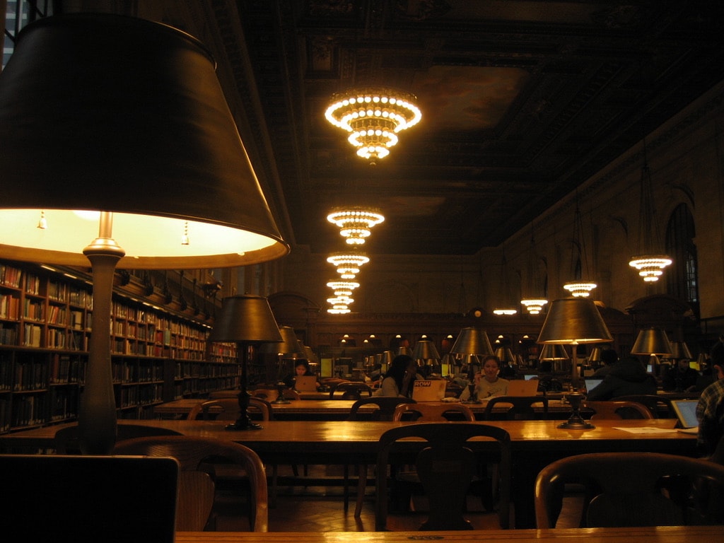 Reading tables beneath warm lamps and chandeliers